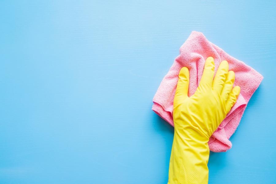 Gloved hand washing a blue wall.