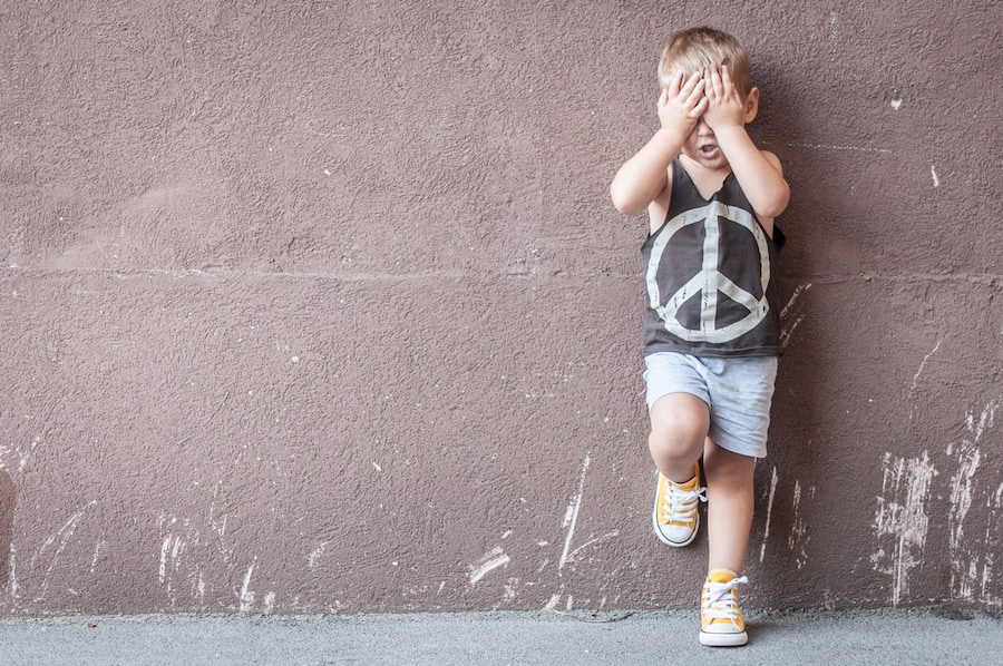 Sad boy over textured wall background with space for text.